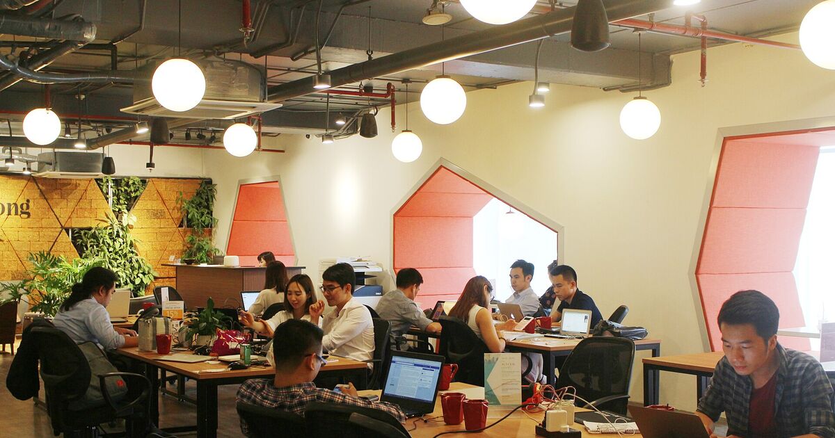 Varias personas trabajando con portátiles en mesas compartidas
