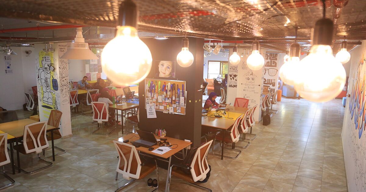 Sala amplia con mesas de trabajo y lámparas colgantes